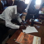 Fr. Paul Mubiana, signs the Certificate of Handover of the Project